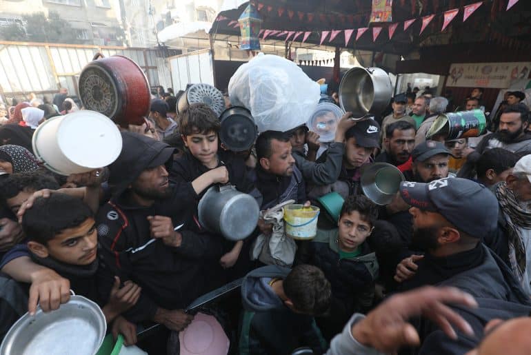 Displaced Palestinian families attempt to secure food from a charity kitchen in Nuseirat refugee camp amid food shortages after Israel restricted aid entry to Gaza following its war on Iran, March 3, 2026. (Photo: Moiz Salhi/APA Images)