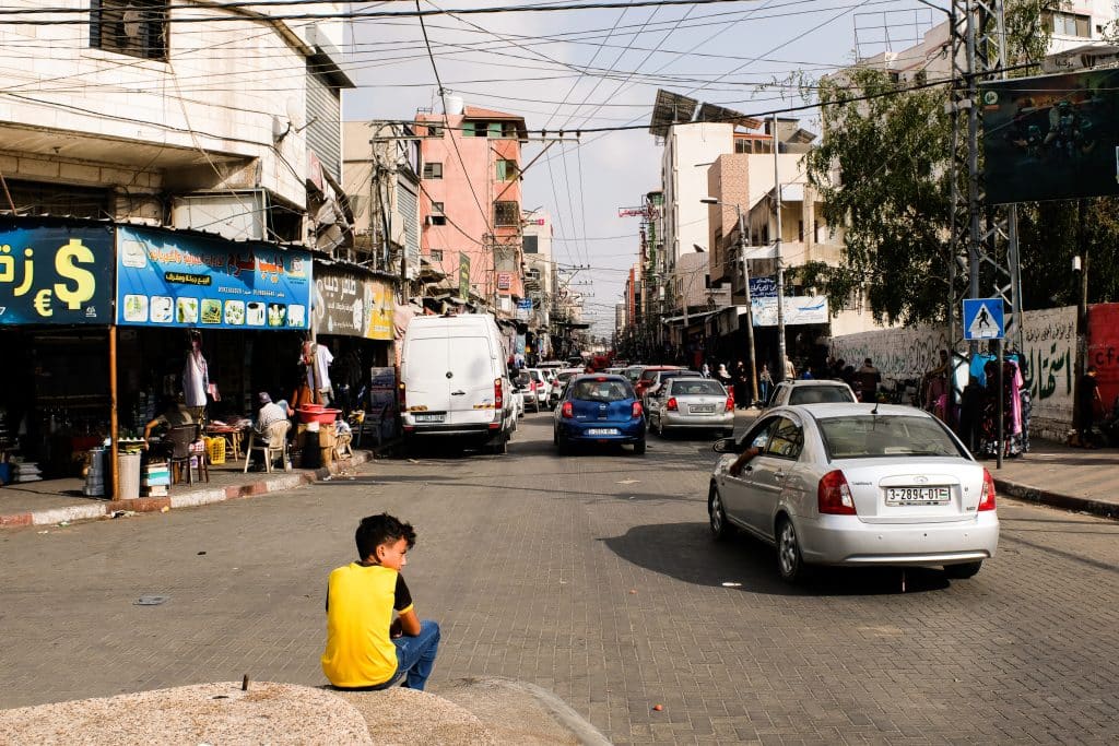 A child sits along a busy street in Gaza, watching traffic and pedestrians pass through old Gaza, September 1, 2022. (Photo: Mahmoud Nasser)