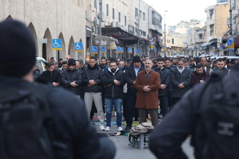 Israeli police watch as Palestinians pray outside the Old City of Jerusalem on the first day of Eid Al Fitr. The Al-Aqsa Mosque compound and other holy sites have remained closed since the start of the war with Iran on February 28, marking the first time the mosque has been shuttered for the holiday since 1967. (Credit Image: © Oren Ziv/dpa via ZUMA Press APA Images, 20 March 2026)