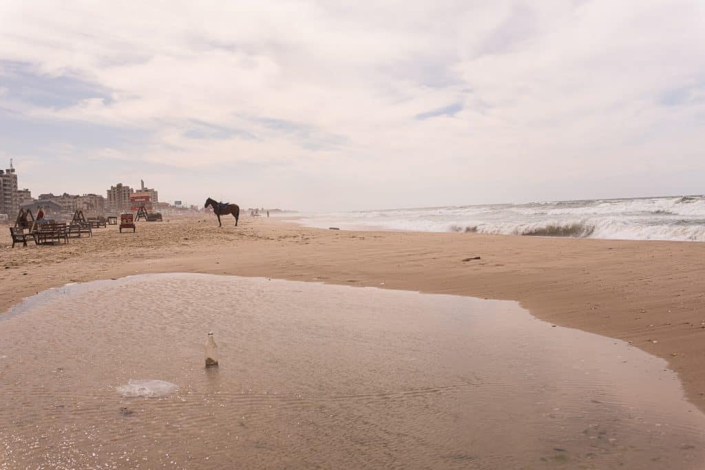 A quiet stretch of Gaza’s coastline as a horse walks across the sand, March 7, 2023. A man rests on a street corner, a common pause in the rhythm of daily life in Gaza, July 8, 2022. (Photo: Mahmoud Nasser)