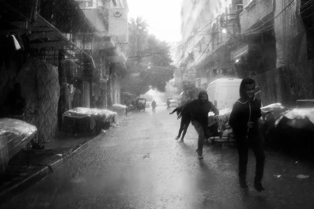 School children make their home through a rain-soaked street, the city slowing under winter weather. (Photo: Mahmoud Nasser)