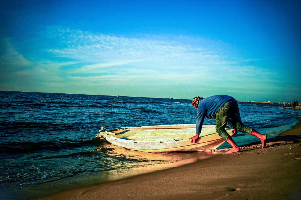 A man pulls a small fishing boat onto the sand at the end of the day, March 11, 2023. (Photo: Mahmoud Nasser)