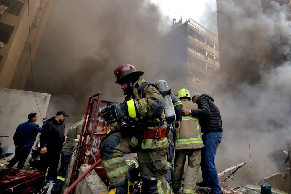 Firefighters and first responders amidst wreckage after and Israeli airstrike.