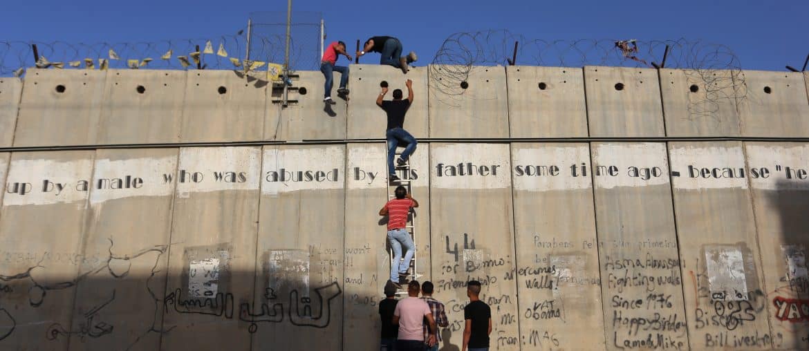 Palestinians who had been prevented from crossing through the Qalandia checkpoint into Jerusalem use a ladder to cross over the separation wall in the town of al-Ram, north of Jerusalem, June 18, 2015. (Photo: Shadi Hatem/APA Images)