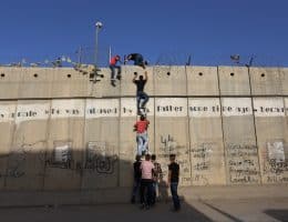 Palestinians who had been prevented from crossing through the Qalandia checkpoint into Jerusalem use a ladder to cross over the separation wall in the town of al-Ram, north of Jerusalem, June 18, 2015. (Photo: Shadi Hatem/APA Images)
