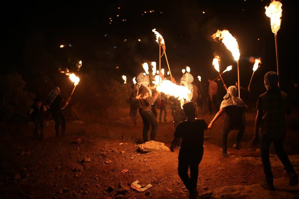 Palestinians carry torches during a night demonstration against the expansion of an Israeli settlement on the lands of Jabal Sabih in the village of Beita, near Nablus, June 23, 2021. (Photo: Shadi Jarar'ah/APA Images)