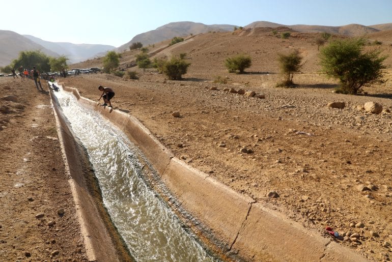 Palestinians swim in al-Auja spring's water in July 2022. (Photo: Wajed Nobani/APA Images)