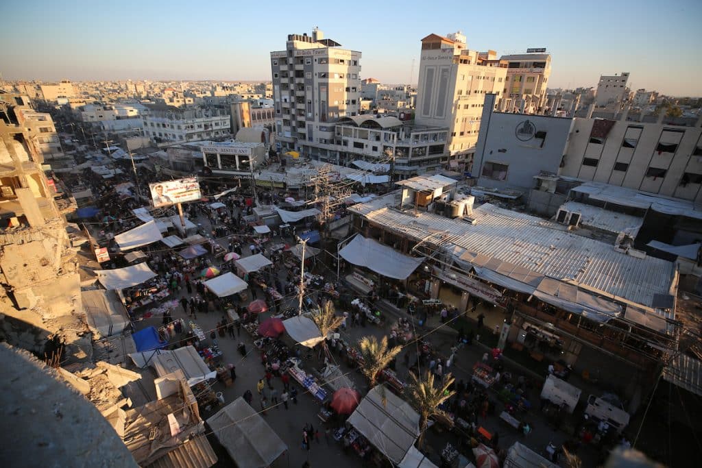 Palestinians walk through a market in the Nuseirat refugee camp in the central Gaza Strip on May 25, 2026, ahead of Eid al-Adha, as vendors display goods on temporary roadside stalls. The market witnessed weak consumer demand and reduced purchasing power amid worsening economic conditions caused by the ongoing war. (Photo: Hassan al-Jedi / APA Images)