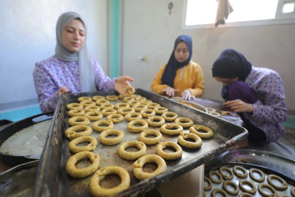 Palestinian women prepare traditional Eid cakes for sale ahead of Eid al-Adha in the Nuseirat refugee camp in the central Gaza Strip on May 25, 2026. Residents are attempting to preserve holiday traditions despite the harsh humanitarian conditions facing Palestinians in the Gaza Strip. (Photo: Hassan al-Jedi/APA Images)