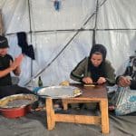 A displaced Palestinian family prepares traditional Eid cookies in their tent in Khan Younis, south Gaza, May 26, 2026. (Photo: Tariq Mohammad/APA Images)