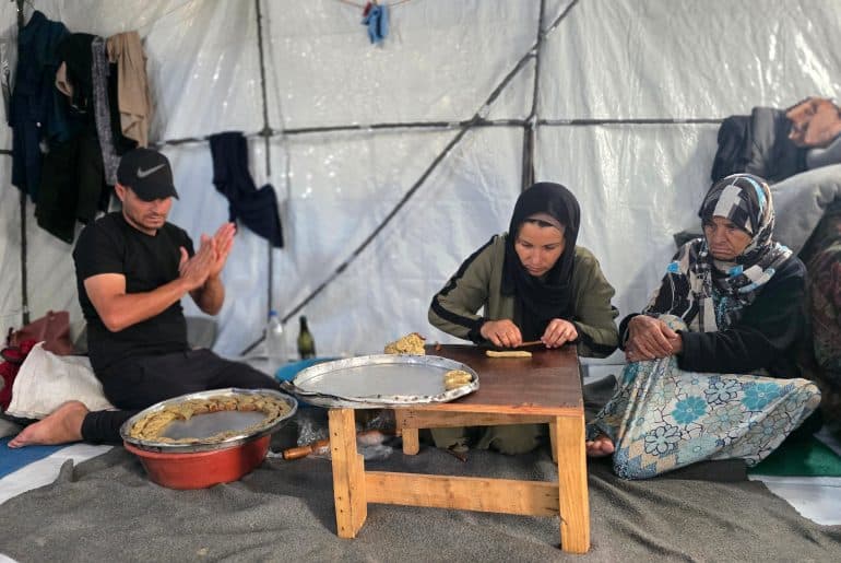 A displaced Palestinian family prepares traditional Eid cookies in their tent in Khan Younis, south Gaza, May 26, 2026. (Photo: Tariq Mohammad/APA Images)