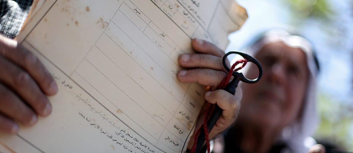A Palestinian man shows deeds to his land during a rally marking the Nakba in Gaza City, on May 15, 2013. (Photo: Ali Jadallah / APA Images)