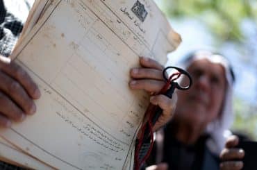 A Palestinian man shows deeds to his land during a rally marking the Nakba in Gaza City, on May 15, 2013. (Photo: Ali Jadallah / APA Images)