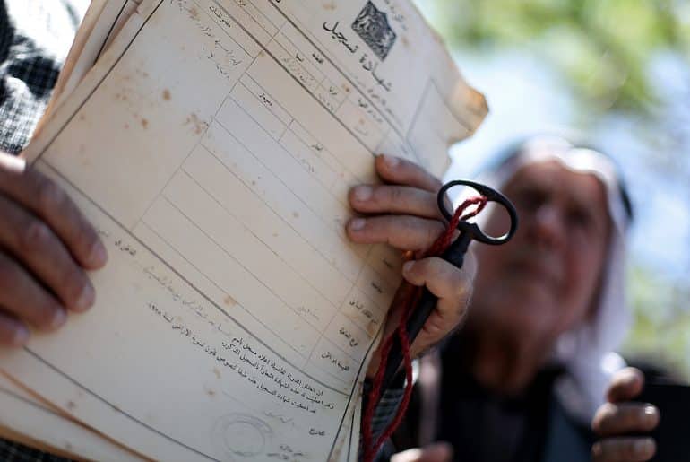 A Palestinian man shows deeds to his land during a rally marking the Nakba in Gaza City, on May 15, 2013. (Photo: Ali Jadallah / APA Images)