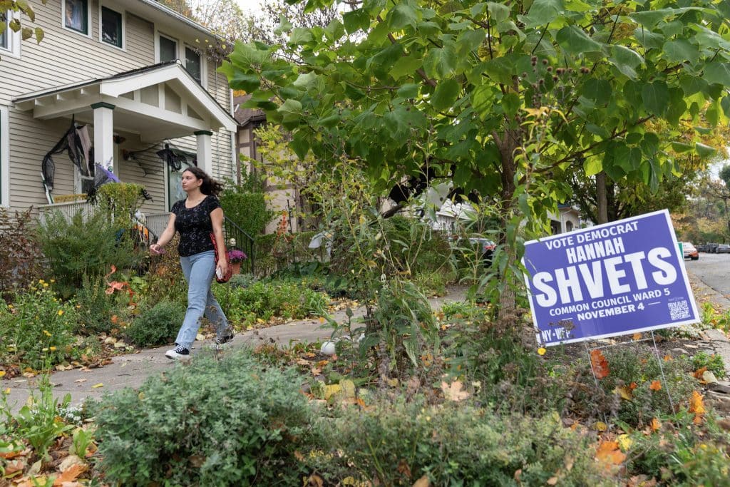 Hannah Shvets walks past a campaign sign as she canvasses on Oct. 19, 2025, in Ithaca, NY. (Photo: Caleb Kaufman)