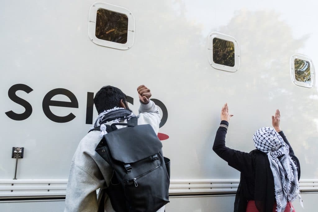 Kamran Ahmed of the Filton25, along with a protester banging on the side of the prison van as it is blocked while leaving the court. (Photo: Aidan Frere-Smith)