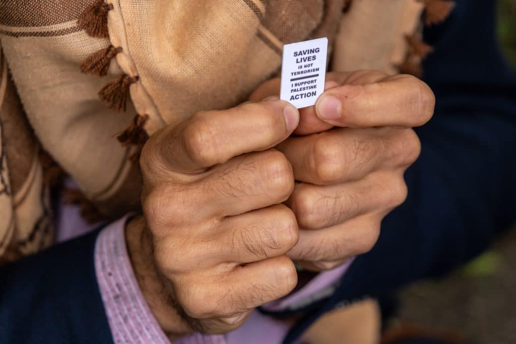 A protester holding a miniature sign stating "Saving lives is not terrorism. I support Palestine Action." (Photo: Aidan Frere-Smith)