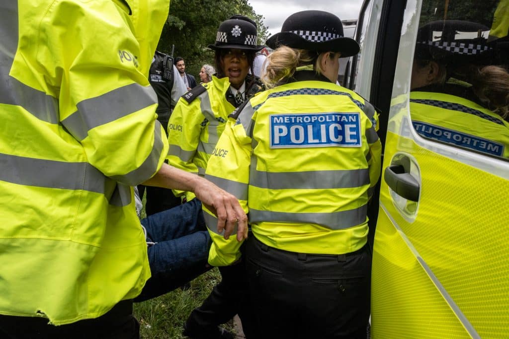 A sign-holding protester is arrested under counterterrorism legislation for showing support for Palestine Action. (Photo: Aidan Frere-Smith)