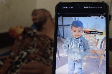 Bahaha Abu al-Ajeen at al-Aqsa Martyrs Hospital with a photo of his son, Rayyan. (Photo: Screenshot from video testimony gathered by Osama Kahlout for Mondoweiss)
