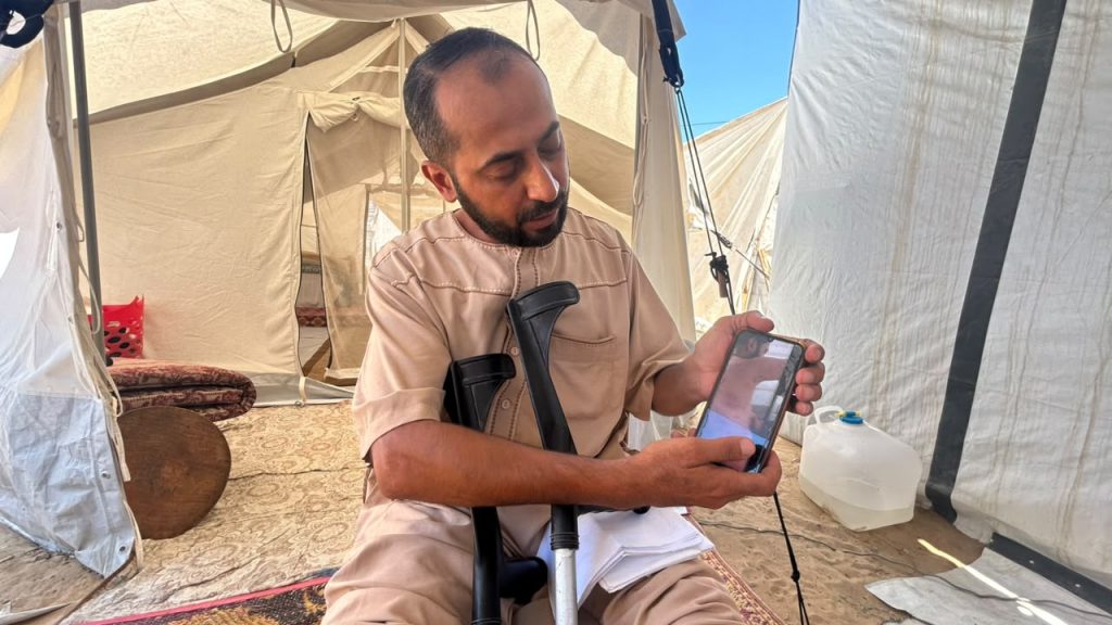Al-Aqqad checks his phone for news on Hamas's dissolution of its Gaza government, hoping it might open the door to being allowed to leave for treatment abroad. (Photo: Mohammed Solaimane).