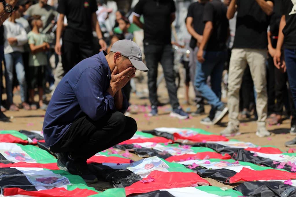 Palestinians attend the funeral of 112 members of the Hassayna and Abu Sharia clans, who were killed in an Israeli strike in November 2023 during the beginning of the Gaza genocide. They were laid to rest on August 4, 2026, after their remains were recovered from underneath the rubble, nearly three years later. (Photo: Bilal Osama/APA Images)