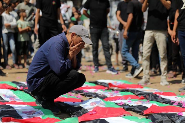 Palestinians attend the funeral of 112 members of the Hassayna and Abu Sharia clans, who were killed in an Israeli strike in November 2023 during the beginning of the Gaza genocide. They were laid to rest on August 4, 2026, after their remains were recovered from underneath the rubble, nearly three years later. (Photo: Bilal Osama/APA Images)