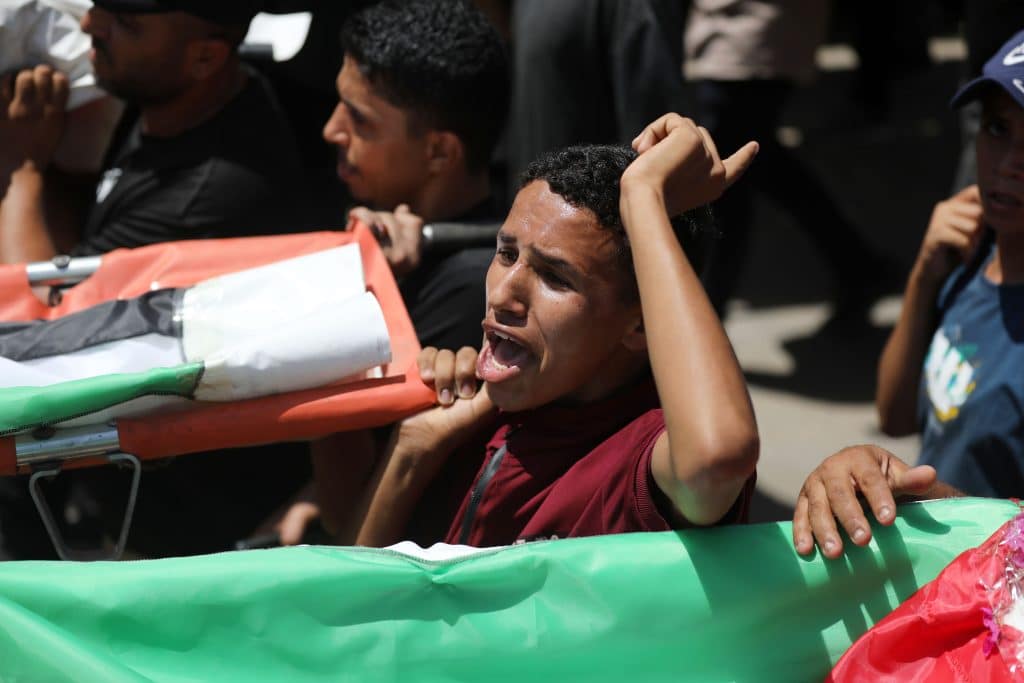 Palestinians attend the funeral of 112 members of the Hassayna and Abu Sharia clans, who were killed in an Israeli strike in November 2023 during the beginning of the Gaza genocide. They were laid to rest on August 4, 2026, after their remains were recovered from underneath the rubble, nearly three years later. (Photo: Bilal Osama/APA Images)