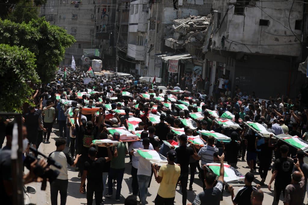 Palestinians attend the funeral of 112 members of the Hassayna and Abu Sharia clans, who were killed in an Israeli strike in November 2023 during the beginning of the Gaza genocide. They were laid to rest on August 4, 2026, after their remains were recovered from underneath the rubble, nearly three years later. (Photo: Bilal Osama/APA Images)