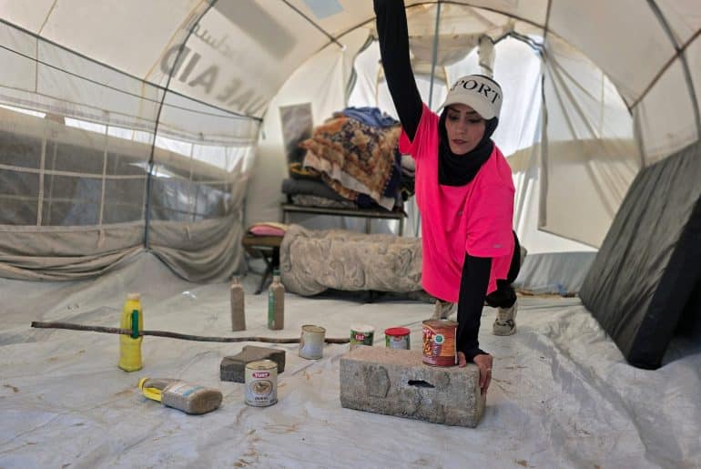 Palestinian fitness trainer Iman al-Mughir uses empty food cans and other waste items as part of her makeshift gym in Mawasi, Khan Younis, August 11, 2026. (Photo: Tariq Mohammad/APA Images)