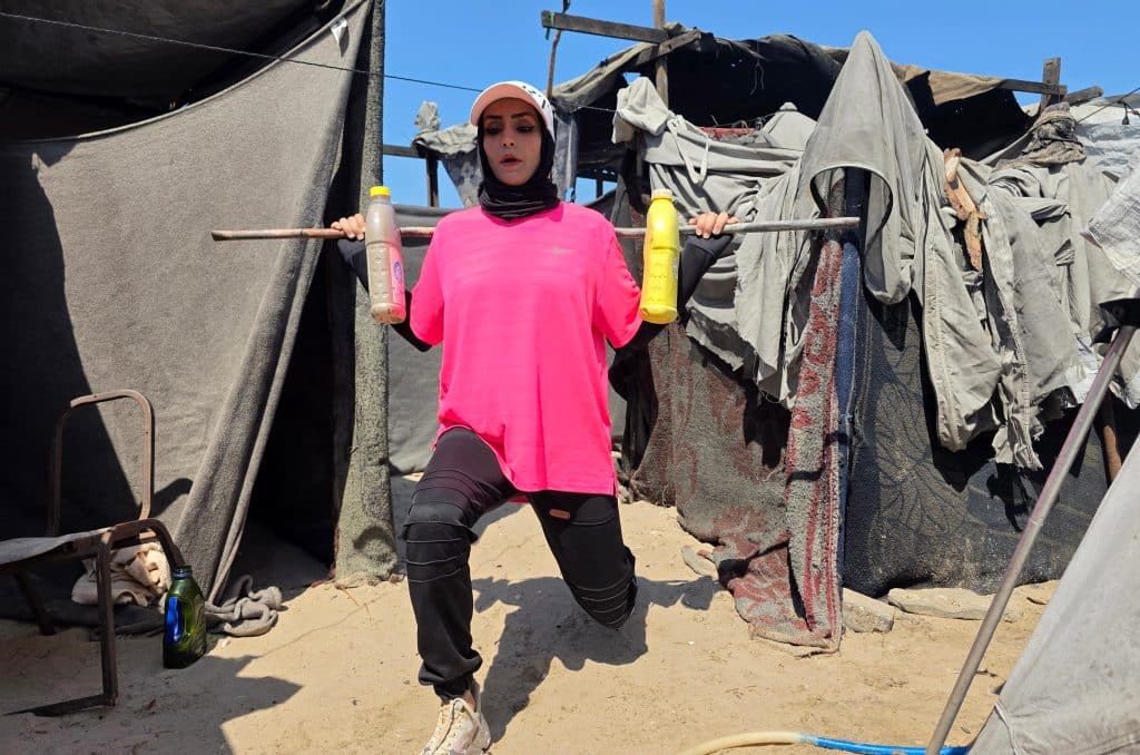 Palestinian fitness trainer Iman al-Mughir uses empty food cans and other waste items as part of her makeshift gym in Mawasi, Khan Younis, August 11, 2026. (Photo: Tariq Mohammad/APA Images)