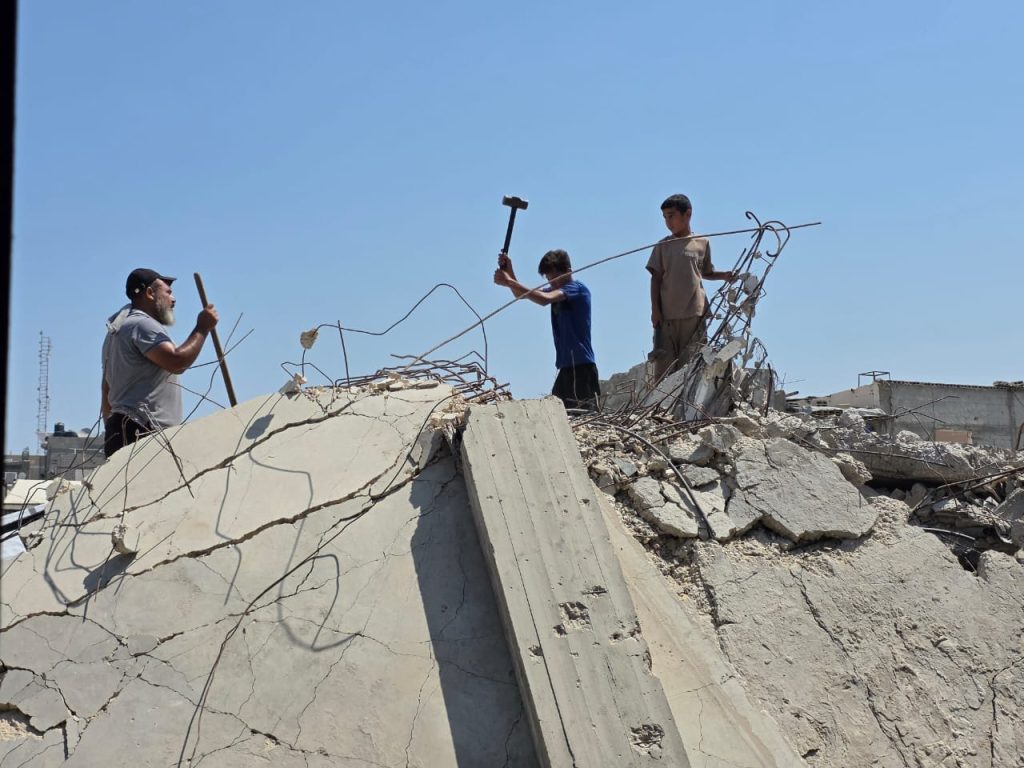 Abdulrahman and his brother go about demolishing their home and clearing its rubble. (Photo: Muhammad Eslayeh)