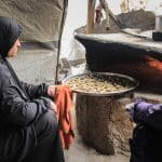 Palestinian women, including widows and wives of those killed, prepare cakes before the arrival of Eid al-Fitr, inside displacement tents in the Nuseirat camp in the central Gaza Strip on March 15, 2026. The women work with simple tools inside the camp to prepare sweets in an attempt to create moments of joy for the children of displaced families despite the conditions of war and displacement. (Photo by Moiz Salhi/ apaimages)
