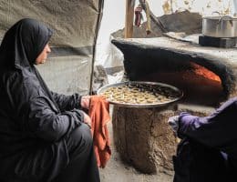Palestinian women, including widows and wives of those killed, prepare cakes before the arrival of Eid al-Fitr, inside displacement tents in the Nuseirat camp in the central Gaza Strip on March 15, 2026. The women work with simple tools inside the camp to prepare sweets in an attempt to create moments of joy for the children of displaced families despite the conditions of war and displacement. (Photo by Moiz Salhi/ apaimages)