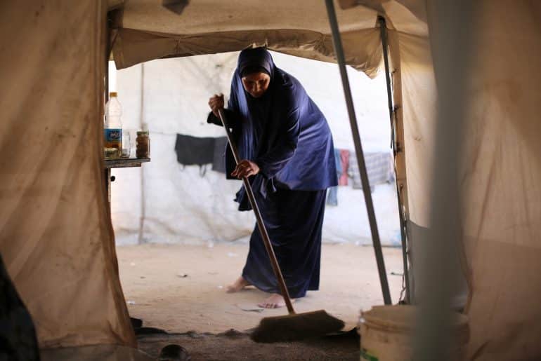 A Palestinian mother bathes her child inside a camp for displaced people in the al-Zawaida area of the central Gaza Strip, on June 17, 2026. Thousands of displaced families continue to endure harsh humanitarian conditions and extreme summer temperatures while living in tents that lack basic services and essential living conditions. (Hassan Jedi / apaimages)