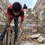 Palestinian shop owners in Khan Younis in southern Gaza remove debris by hand and rebuild their damaged stores using stones and red clay, December 27, 2025. (Photo: Tariq Mohammad/APA Images)