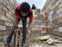 Palestinian shop owners in Khan Younis in southern Gaza remove debris by hand and rebuild their damaged stores using stones and red clay, December 27, 2025. (Photo: Tariq Mohammad/APA Images)