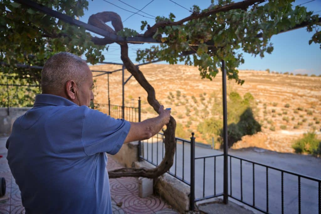 Muhammad Khamis standing in his porch pointing to the Kufr Malik street. (Photo: Qassam Muaddi/Mondoweiss)