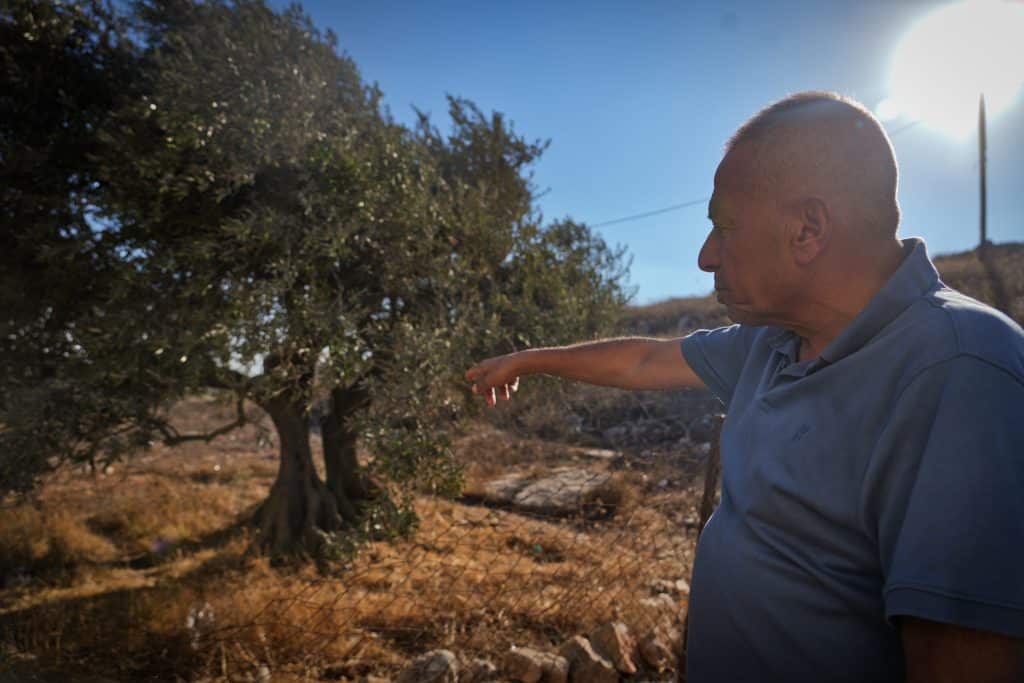 Muhammad Khamis points to where Israeli settlers stood during a settler attack in July. (Photo: Qassam Muaddi/Mondoweiss)