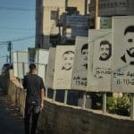 A Palestinian teenager walks past stenciled images of Deir Jarir martyrs slain by the Israeli army or settlers in Deir Jarir. (Photo: Qassam Muaddi/Mondoweiss)