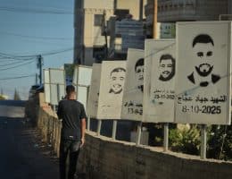 A Palestinian teenager walks past stenciled images of Deir Jarir martyrs slain by the Israeli army or settlers in Deir Jarir. (Photo: Qassam Muaddi/Mondoweiss)