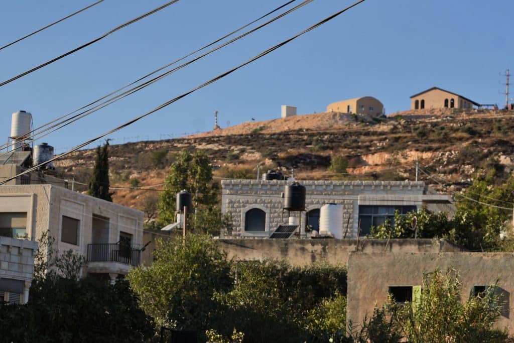 Israeli settler outpost on the slope of Mount al-Asour overlooking Palestinian homes. (Photo: Qassam Muaddi/Mondoweiss)