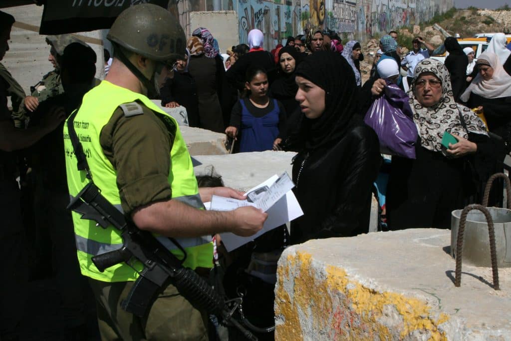 Israeli soldiers checking IDs of Palestinian women as they pass security checks at Qalandia checkpoint on the outskirts of the West Bank city of Ramallah on August 13, 2010. (Photo: Wagdi Eshtayah/APA Images)
