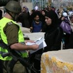 Israeli soldiers checking IDs of Palestinian women as they pass security checks at Qalandia checkpoint on the outskirts of the West Bank city of Ramallah on August 13, 2010. (Photo: Wagdi Eshtayah/APA Images)