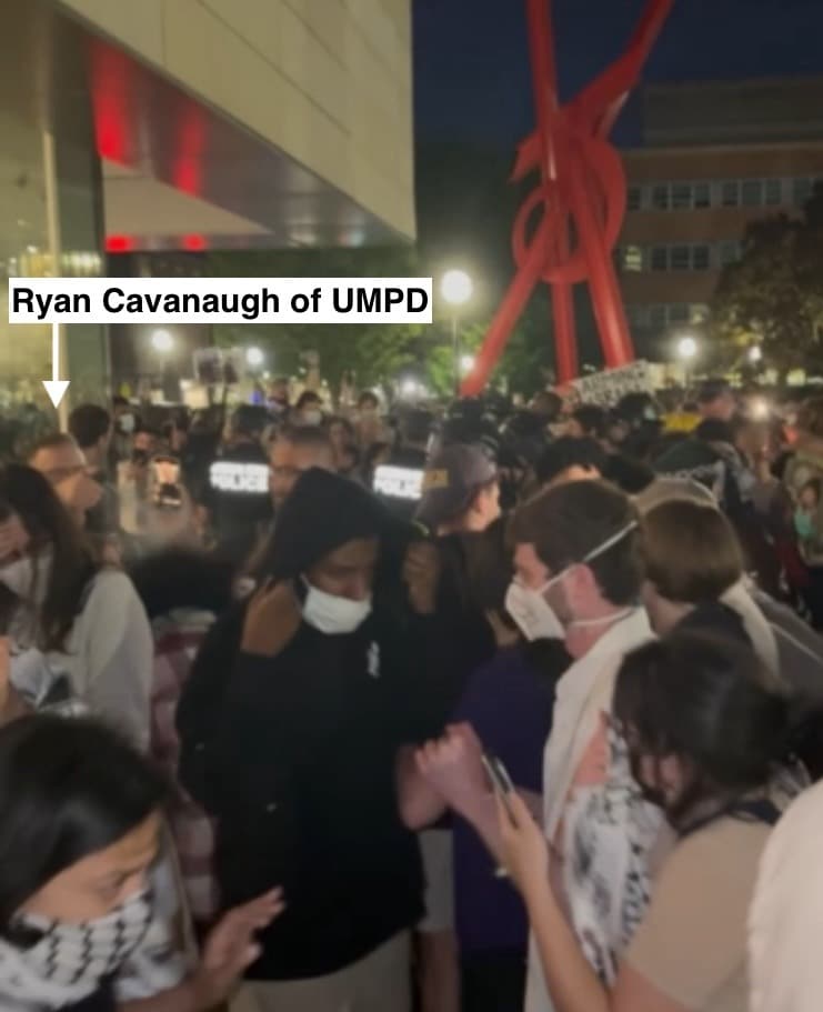 Detective Sergeant Ryan Cavanaugh of the University of Michigan Police Department (on left) pepper spraying the crowd outside the UM Museum of Art on May 3, 2024. The crowd had gathered to call on the UM Regents, some of whom were inside the museum for an event, to divest from Israel. Four protestors were detained, arrested, and given trespass warnings in that protest. (Photo: TAHRIR Coalition)