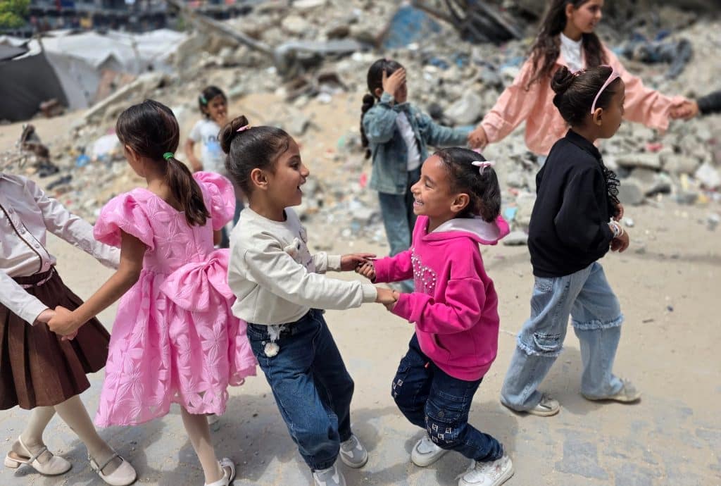 Displaced Palestinian children play on the first day of Eid al-Adha among tents and destroyed buildings, Khan Younis, May 27, 2026. (Photo: Tariq Mohammad/APA Images)